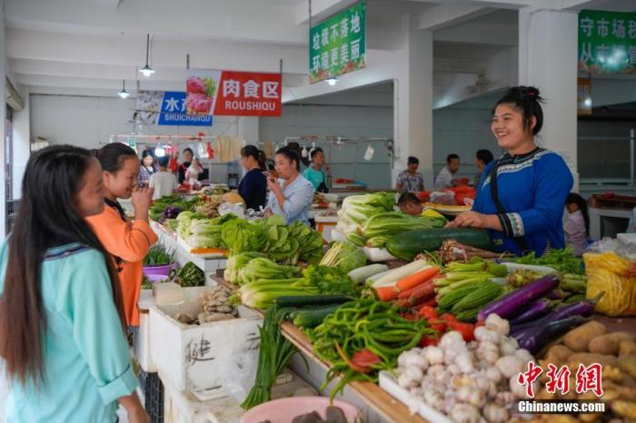 貴州省榕江縣易地扶貧搬遷安置點臥龍小區(qū)，侗族婦女石本艷(右一)在菜市場賣菜。<a target='_blank' >中新社</a>記者 賀俊怡 攝